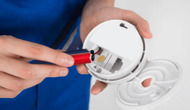 Close-up of hand holding smoke detector battery