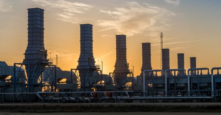 Photographed silhouettes of industrial energy plant structures, representing utility scale ultra-low carbon production facility for low-carbon hydrogen.