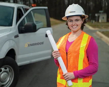 A person in an Enbridge helmet holding a roll of paper