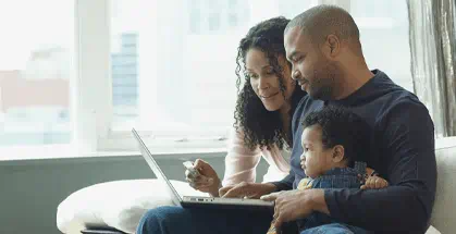 Couple sitting on couch looking at laptop with a child