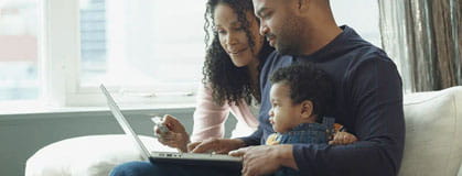 Couple with child sitting on couch paying bills