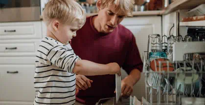 Father and son loading dishes in the dishwasher