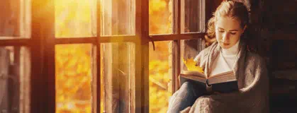 A person sitting by the window reading a book