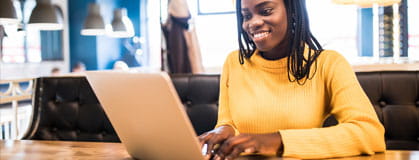 African american woman with laptop and phone in a cafe