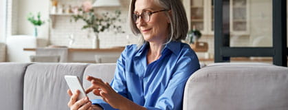 Relaxed mature woman holding smartphone