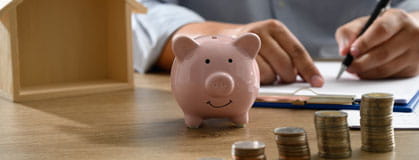 Piggy bank with coins before it and tax documentation being signed. 