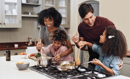 Shot of a family of four cooking together in their kitchen at home.