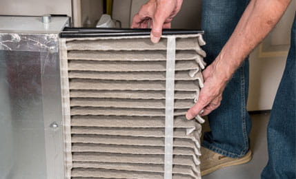 Senior man changing a dirty air filter in a HVAC Furnace