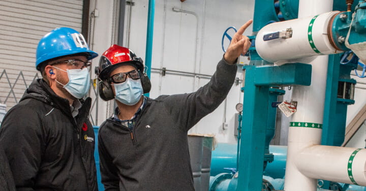 Two technicians examine part of the heating and cooling system at Maple Leaf Foods.