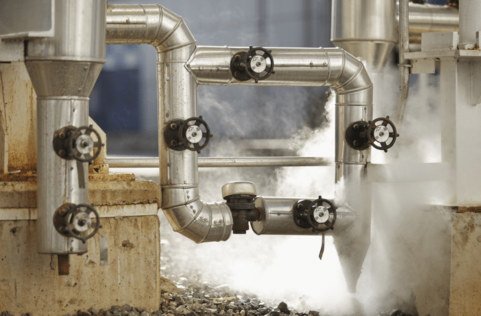 Pipes at an industrial facility emitting steam.