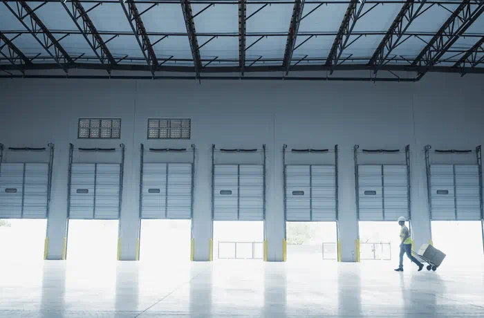 Man walking in front of six open loading docks.