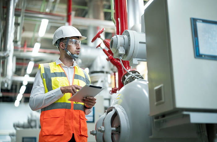 Man in a hard hat inspecting boiler room