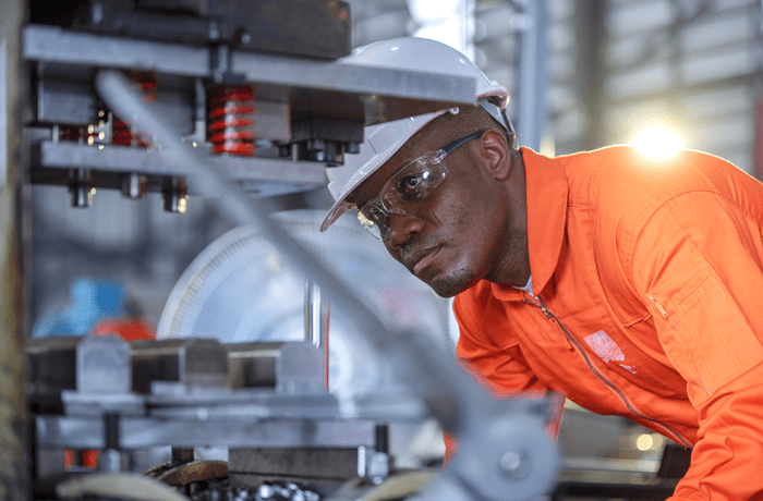 Man in hard hat examining factory equipment 