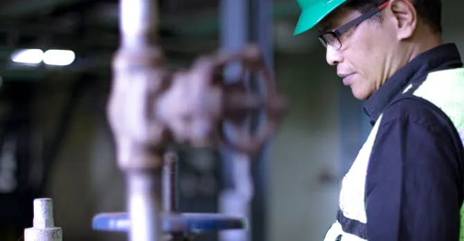 Man in hard hat inspects mechanical equipment