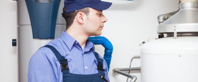 Man holding clipboard examining hot water heater