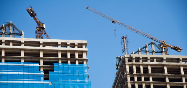 Two buildings under construction, with a crane in the background. 