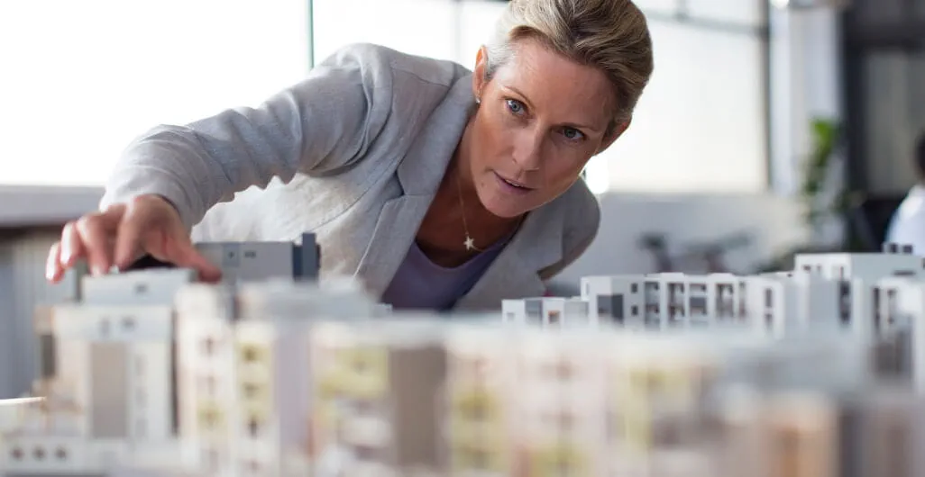 Woman leaning over table examining architectural model