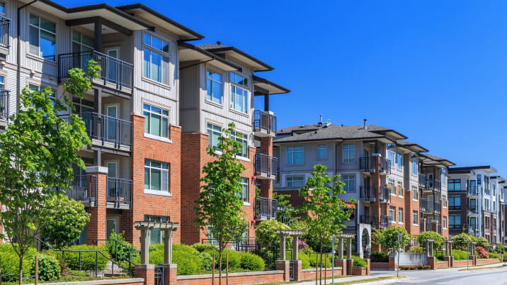 Exterior view of a four storey modern condominium development on a clear day. 