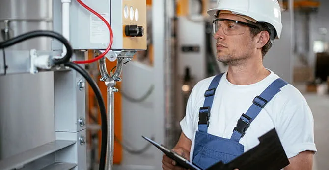 Man wearing a hard hat and inspecting equipments.