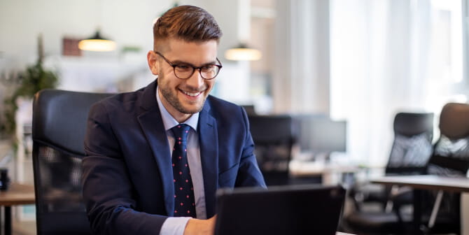 A man looking at his laptop and smiling.