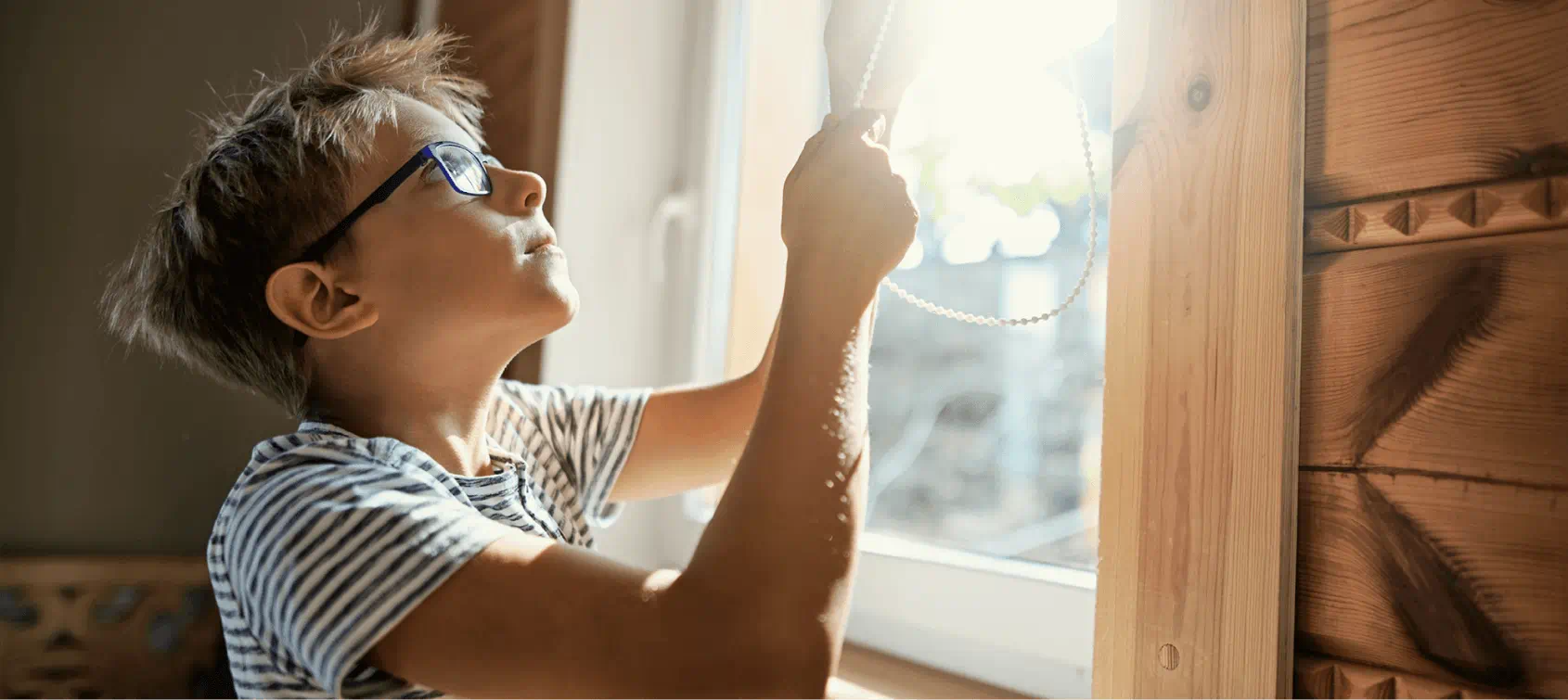 Little boy closing the blinds to save energy