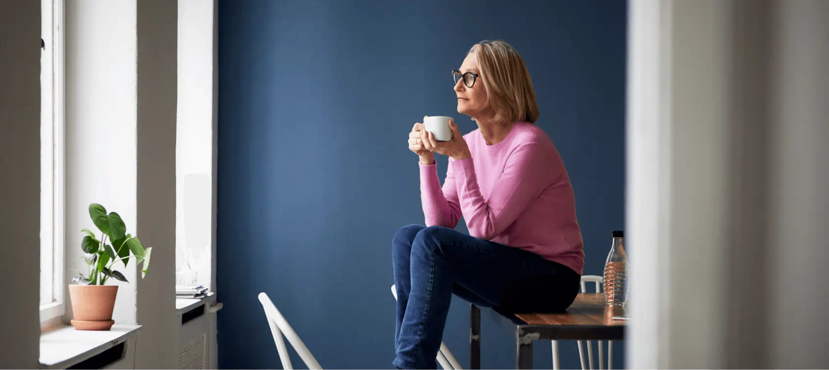 Woman enjoying a cup while sitting at her table while looking out the window