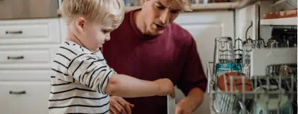 Father and son loading dishes in the dishwasher