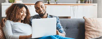 Couple sitting on couch looking at laptop