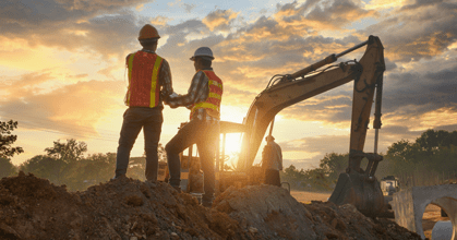 Two people in safety vests and helmets standing in a construction site