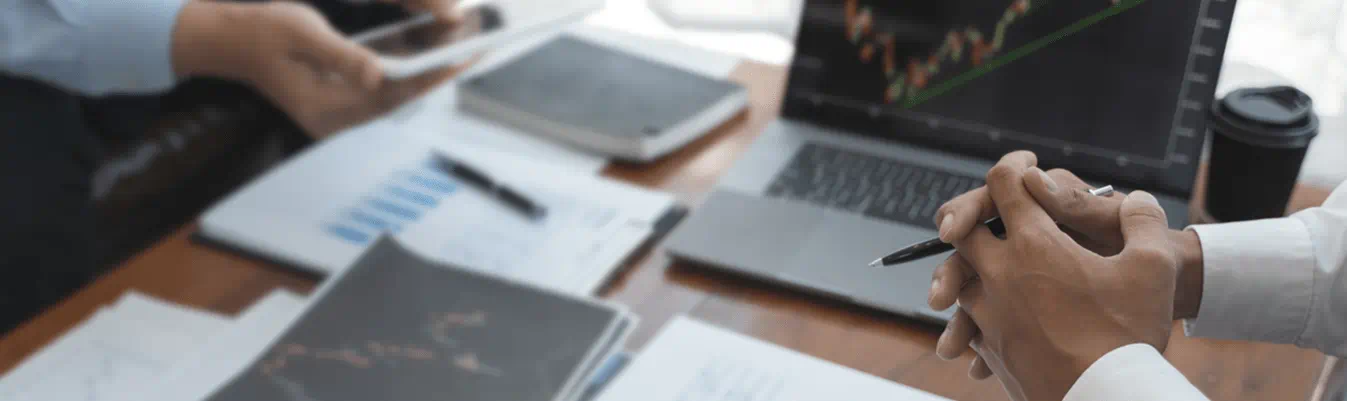 A close-up of two people's hands with laptops and papers