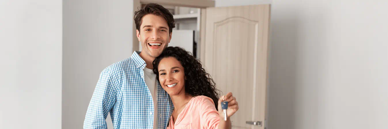 A couple holding a key in a room with boxes 